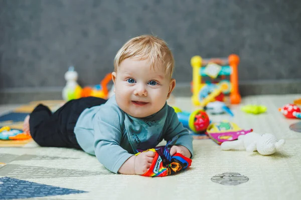 The baby lies on a thermal mat and plays. Self-development of a newborn child. Toys for child development.