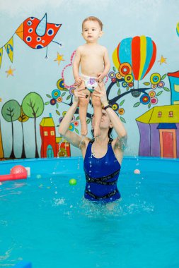 Küçük bir çocuk bir arabayla havuzda yüzüyor. Çocuklara yüzmeyi öğretmek. Çocuk yüzme okulu.