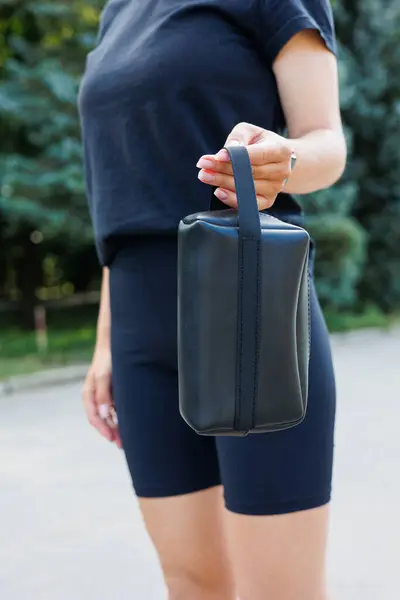 Black leather bag made of genuine leather in female hands. Leather products.