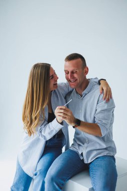 Genç mutlu çift, erkek ve kadın, pozitif bir hamilelik testi yaptılar ve seviniyorlar. Hamilelik Testi