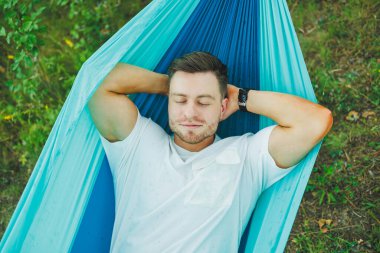 Hamaktaki bir adam doğada oturur ve dinlenir. Sadece doğadaki eğlence kavramı..