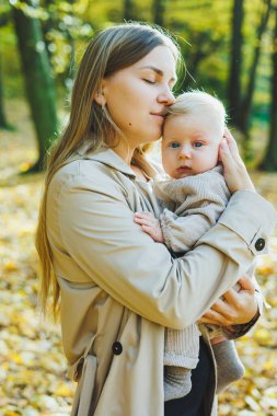 Mutlu genç anne, sıcak bir bahar ya da yaz gününde parkta oğluna sarılıyor. Güneş bir elma bahçesinde ya da parkta parlıyor. Anne ve oğul doğada aile kavramı