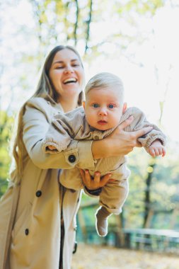 Mutlu genç anne, sıcak bir bahar ya da yaz gününde parkta oğluna sarılıyor. Güneş bir elma bahçesinde ya da parkta parlıyor. Anne ve oğul doğada aile kavramı