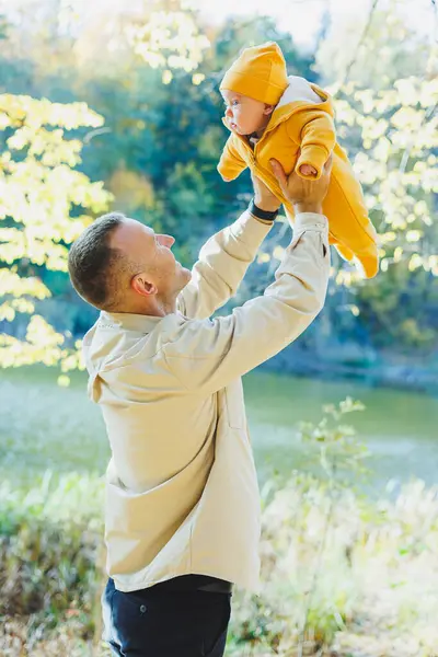 Young dad and little son in the park outdoors. Dad holds and kisses his son. Happy father and son.