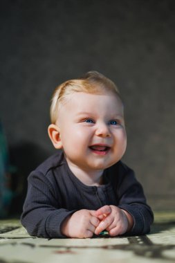 6 aylık küçük bir çocuk bir mindere uzanıp oyuncaklarla oynuyor. Bebeğin kendi kendini geliştirmesi.