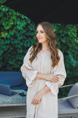Yazlık bir kafede terasta elbise giymiş genç bir kadın. Gündelik şık yaz kıyafetleri içinde bir kadın.
