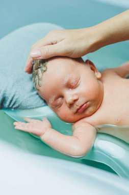 Kürsüde bir bebeği küvette yıkamak. Bebeğin doğumdan sonra evde ilk banyosu..