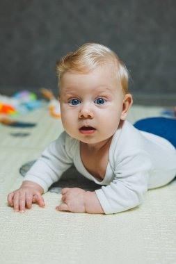 5 aylık bir bebek gülümsüyor ve gelişim paspasının üzerinde yatıyor. Çocuğun kişisel gelişimi.
