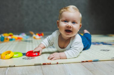 Beş aylık tatlı bir çocuk halıda yalan söylüyor ve oynuyor. Çocuk yerde yatıyor. Küçük şirin bir bebek emeklemeyi öğreniyor..