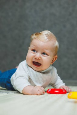 Beş aylık tatlı bir çocuk halıda yalan söylüyor ve oynuyor. Çocuk yerde yatıyor. Küçük şirin bir bebek emeklemeyi öğreniyor..