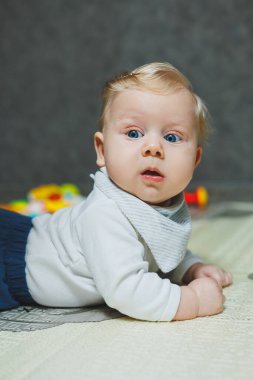 Beş aylık tatlı bir çocuk halıda yalan söylüyor ve oynuyor. Çocuk yerde yatıyor. Küçük şirin bir bebek emeklemeyi öğreniyor..