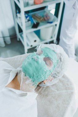 Cildiyeci randevusunda bir kadın uzanıyor. Yüz bakımı. Bir kadının yüzüne maske takmak