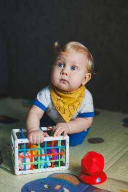 Çocuk paspasın üzerinde yatıyor, yumuşak toplarla oynuyor. Bebeğin el becerileri için eğitici oyuncaklar. Çocuk gelişimi. Duyusal deneyim