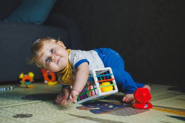 Çocuk paspasın üzerinde yatıyor, yumuşak toplarla oynuyor. Bebeğin el becerileri için eğitici oyuncaklar. Çocuk gelişimi. Duyusal deneyim