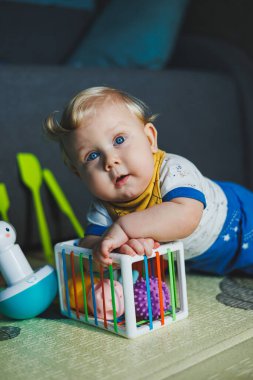 Çocuk paspasın üzerinde yatıyor, yumuşak toplarla oynuyor. Bebeğin el becerileri için eğitici oyuncaklar. Çocuk gelişimi. Duyusal deneyim