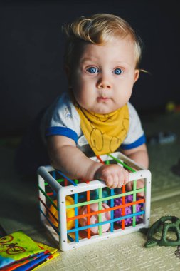 Çocuk paspasın üzerinde yatıyor, yumuşak toplarla oynuyor. Bebeğin el becerileri için eğitici oyuncaklar. Çocuk gelişimi. Duyusal deneyim