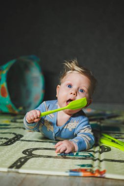 5 aylık bir erkek bebek halıya uzanıyor ve silikon oyuncaklarla oynuyor. Çocuğun kişisel gelişimi.