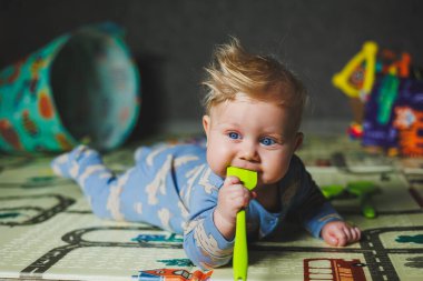 5 aylık bir erkek bebek halıya uzanıyor ve silikon oyuncaklarla oynuyor. Çocuğun kişisel gelişimi.