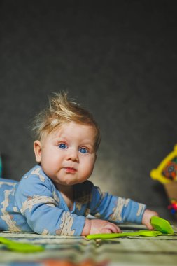 Küçük bir çocuk termal mindere uzanıp oyuncaklarla oynuyor. Çocuk oyunları için halı.