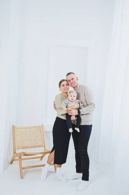 Gülümseyen anne ve baba kucağında bir çocuk. Anne, baba ve kollarındaki gülümseyen bebek beyaz arka planda izole edilmiş. Mutlu genç aile.