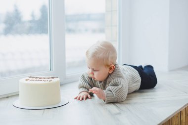 Gülümseyen 6 aylık bir çocuk lezzetli bir pastaya doğru sürünüyor..