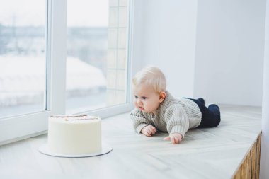 Gülümseyen 6 aylık bir çocuk lezzetli bir pastaya doğru sürünüyor..