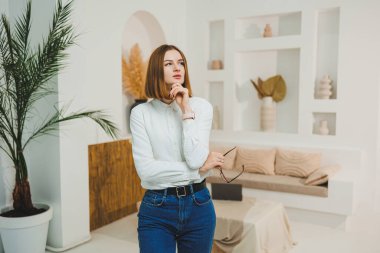 Açık alanda gözlüklü hoş bir kadın, iş yerinde çalışan, rahatlayan, uzaktan çalışan, beyaz tişört ve kot pantolon giyen.