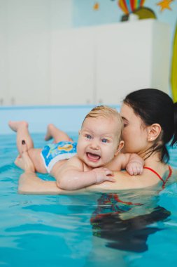 Antrenör bebeğe yüzme, çocuklar için yüzme havuzu öğretiyor. Çocuk gelişimi.