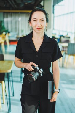 Genç bir bayan fotoğrafçı bir kafede dizüstü bilgisayarda çalışıyor. Kadın fotoğrafçı dizüstü bilgisayardaki fotoğrafları düzeltiyor.