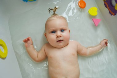 6 aylık bir bebek banyoda banyo yapıyordur. Bebek cilt bakımı. Bebek hijyeni.