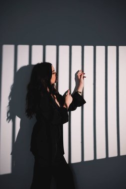 Siyah saten takım elbiseli güzel bir kadın. Stüdyo ışıklandırmasının arka planında takım elbiseli şık bir kadın.