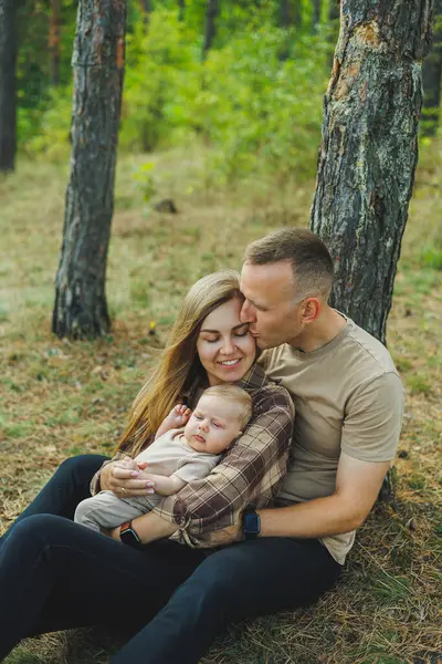 Mutlu bir aile, güneşli bir yaz gününde yeni doğmuş bebekleriyle parkta yürüyen güzel ve genç bir aile..