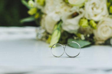 Çiçeklerin arka planında yeni evliler için değerli altın yüzükler. Bir çift için alyans..
