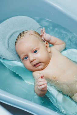 Bebek hijyeni. Bebek küvette yatıyor ve banyo yapıyor. Bebek suda banyo yapıyor..