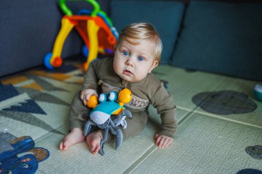 Çocuk renkli oyuncak bloklarıyla oynuyor. Çocuklar oynar. Küçük çocuk güneşli beyaz yatak odasındaki karanlık zeminde oyuncaklardan kule inşa ediyor. Bebek ve bebek için eğitici bir oyun. Çocuklar oyuncak ev yapar.