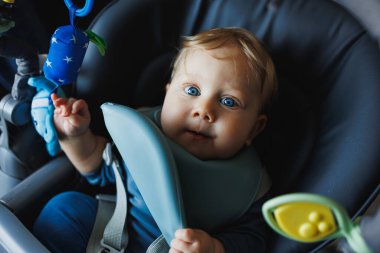 Bebek yüksek sandalyede oturan örülü süveter giyiyor ve acıkıyor, kaşık tutuyor ve püre veya lapa yiyor, sarı şişede elma ve suyun tadını çıkarıyor, beyaz arka planda izole bir şekilde poz veriyor..