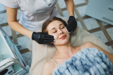 Lateks eldivenli bir güzellik uzmanının elleri bir kadının yüzüne masaj yapar. Yüz masajı. Kadınlar için yüz bakımı prosedürü