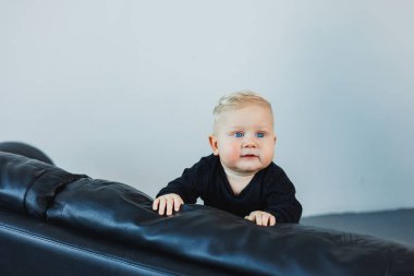 6 aylık şirin Kafkas ve Afrikalı melez bebek öksürüyor. Yüksek sandalyesinde oturuyor ve ilk katı yemeğini yiyor.