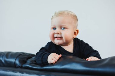 6 aylık şirin Kafkas ve Afrikalı melez bebek öksürüyor. Yüksek sandalyesinde oturuyor ve ilk katı yemeğini yiyor.