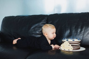 10 aylık bir erkek bebek lezzetli bir pastanın yanında yatıyor. Küçük bir çocuk için bir pasta..