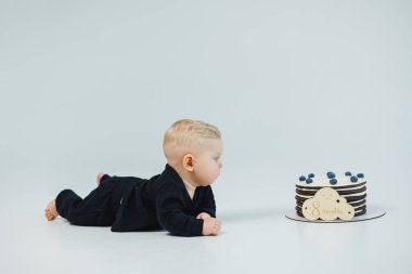 8 aylık beyaz bir geçmişi olan küçük bir çocuk bir pastanın yanında yatıyor. Küçük bir çocuk için tatlı pasta..