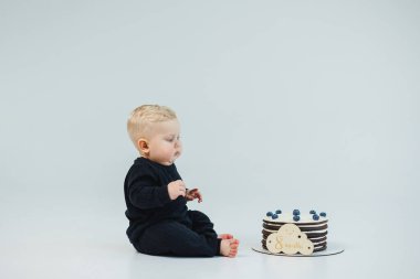 8 aylık beyaz bir geçmişi olan küçük bir çocuk bir pastanın yanında yatıyor. Küçük bir çocuk için tatlı pasta..