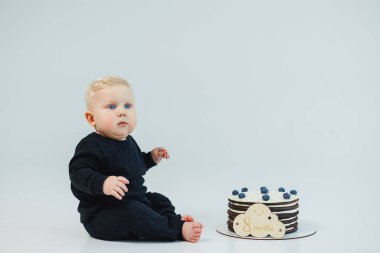 8 aylık beyaz bir geçmişi olan küçük bir çocuk bir pastanın yanında yatıyor. Küçük bir çocuk için tatlı pasta..