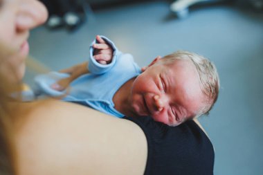 Annesinin kollarında yatan yeni doğmuş bir bebeğin yakın çekimi..