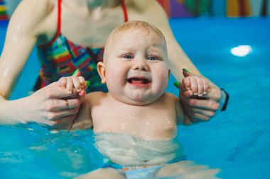 Bebekler için yüzme havuzu. Bir bebek koçla yüzmeyi öğrenir.