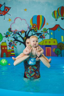 Bebekler için yüzme havuzu. Bir bebek koçla yüzmeyi öğrenir.