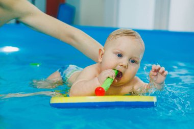 Bebekler için yüzme havuzu. Bir bebek koçla yüzmeyi öğrenir.