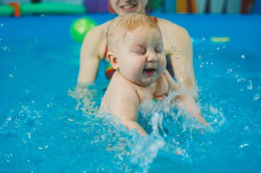 Bebekler için yüzme havuzu. Bir bebek koçla yüzmeyi öğrenir.