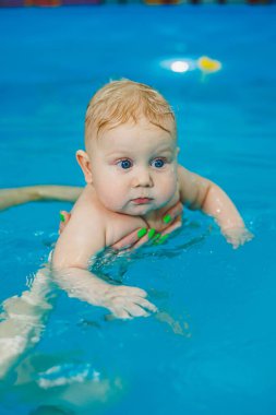 Bebekler için yüzme havuzu. Bir bebek koçla yüzmeyi öğrenir.