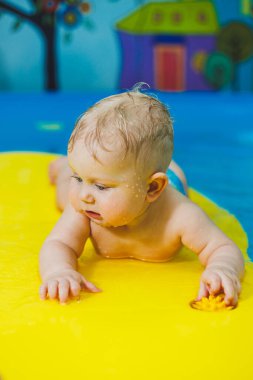 Bebekler için yüzme havuzu. Bir bebek koçla yüzmeyi öğrenir.